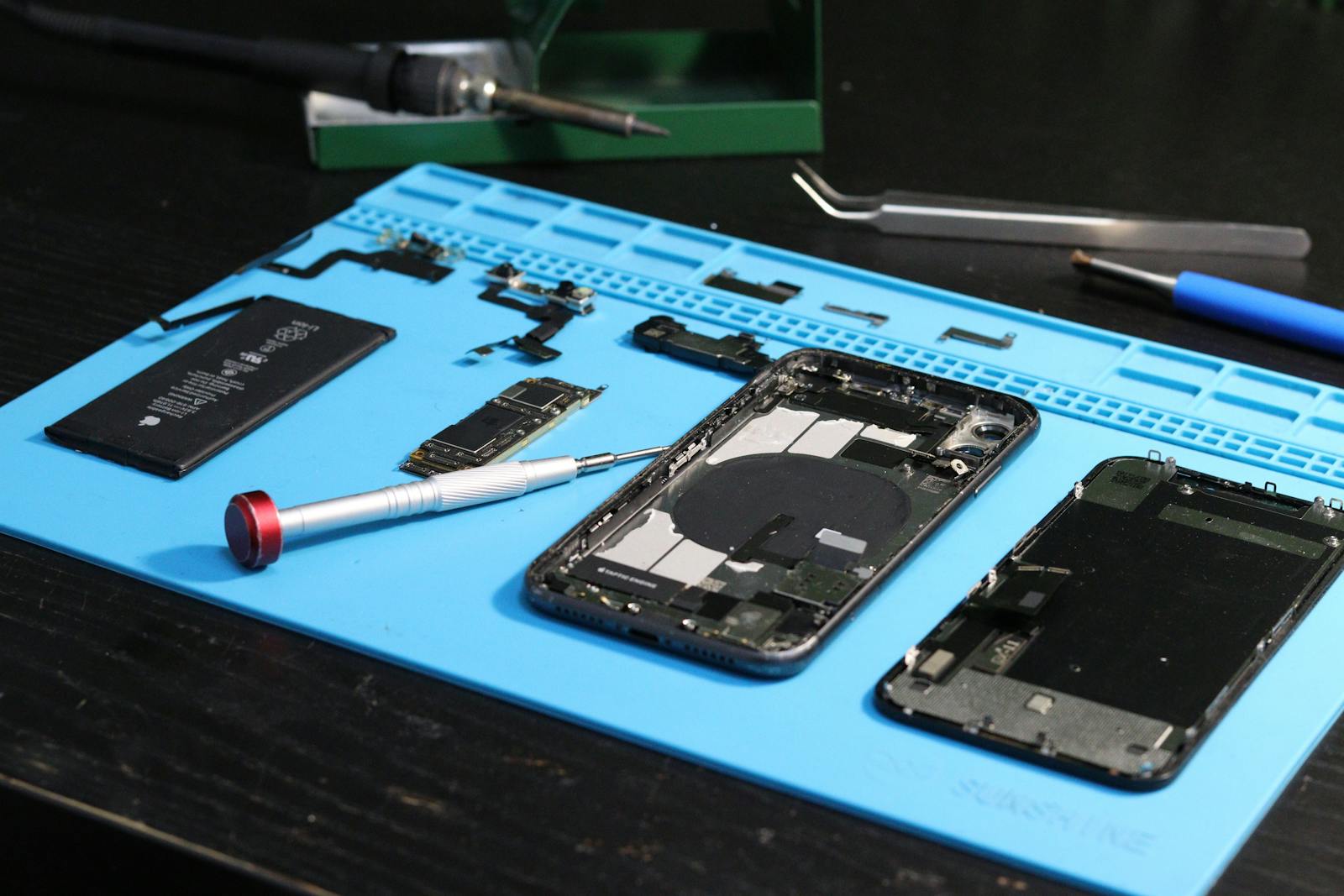 Smartphone-Reparatur: zerlegte Bauteile auf blauer Reparatur-Matte mit Werkzeug, PC Service P&ouml;schl
